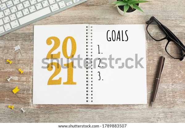 New Year goals List\
2021 with notebook written in handwriting about plan listing of new\
year goals and resolutions setting. flat lay style. Christmas\
planning concept.