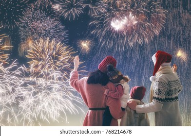 New Year Holiday. Parents And Daughters Children Girls Are Watching Fireworks. Happy Family On Snowy Winter Walk In Nature. Holidays Winter Season.