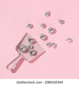 New Year party creative layout with  dico balls christmas decoration in dustpan on pastel pink background. 80s or 90s retro fashion aesthetic concept. New Year celebration idea.