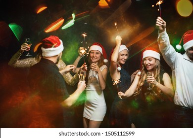 New Year Party In Night Club, Christmas Celebration Atmosphere. Friends Dancing With Champagne Glasses And Sparkles, Modern Youth Life