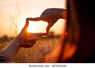 New year planning and vision concept, Close up of woman hands making frame gesture with sunset, Female capturing the sunrise.