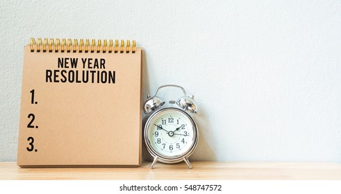 New Year Resolution On A Notepad And Alarm Clock On Wood Table