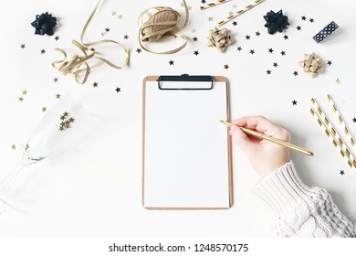 New Year Resolution, Wish List Concept. Blank Notebook Mock-up. Golden Party Decoration. Confetti And Wine Glass On White Table Background. Flat Lay, Top View.