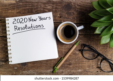 New year resolutions 2020 on desk. 2020 goals with notebook, coffee cup and eyeglasses on wooden background. Goal, plan, strategy, action, idea concept - Shutterstock ID 1539984287