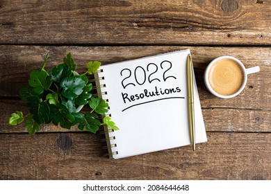 New year resolutions 2022 on desk. 2022 new year resolutions on wooden table with coffee cup, notebook and plant. New year goals, plan, resolutions, business concept. Copy space - Shutterstock ID 2084644648