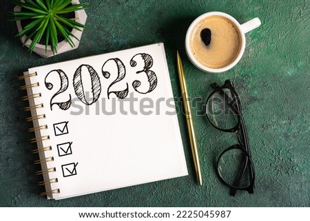 New year resolutions 2023 on desk. 2023 resolutions list with notebook, coffee cup on table. Goals, resolutions, plan, action, checklist concept. New Year 2023 background. Copy space