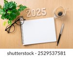 New year resolutions 2025 on desk. 2025 resolutions list with notebook, coffee cup on table. Goals, resolutions, plan, action concept. New Year 2025 template, copy space