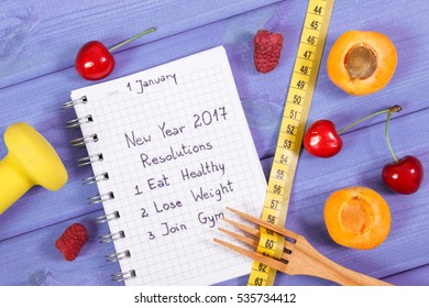 New Year Resolutions Or Goals Written In Notebook, Fresh Fruits, Dumbbells For Fitness And Tape Measure With Wooden Fork