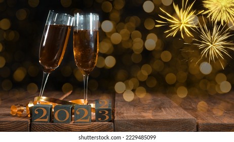 New Year Sylvester New Year's Eve celebration holiday greeting card background - Cubes with change of year from 2022 to 2023 and sparkling wine or champagne glasses toasting on table and fireworks - Shutterstock ID 2229485099
