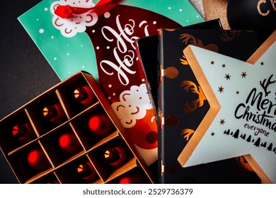 New Year toy with Christmas decorations, notepad, round wooden coasters, gifts and pine cone on a black wooden background. - Powered by Shutterstock