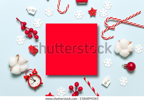 New year winter holiday xmas\
concept with creative red frame, festive decor, toy, candy cane,\
berry branches on a blue background for merry christmas and new\
year