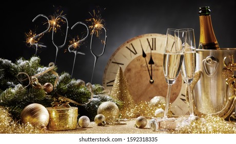 New Years 2020 Celebration Festive Postcard Or Poster Concept With Decorations, Sparkling Digits, Bucket With Champagne And Two Crystal Glasses Against Vintage Clock Face On Dark Background