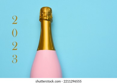New Years 2023 Concept. A Pink Champagne bottle on a blue teal background, with the text 2023 on one side. - Shutterstock ID 2211296555