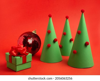 New Year's Card. Decorative Christmas Tree, Ball And A Gift Box On A Bright Red Background. Christmas Trinkets