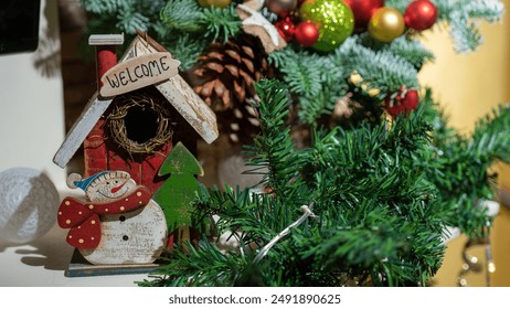 New Year's composition of Christmas tree branches, red, green and yellow balls and other New Year decorations. Wooden house with snowman. - Powered by Shutterstock