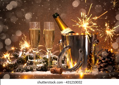 New Years Eve celebration background with pair of flutes and bottle of champagne in bucket and a horseshoe as lucky charm