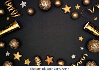 New Years Eve Frame Of Glittery Gold Stars, Streamers, Decorations And Noisemakers. Above View On A Black Background.