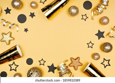 New Years Eve Frame Of Shiny Stars, Streamers, Decorations And Noisemakers. Overhead View On A Champagne Gold Background.