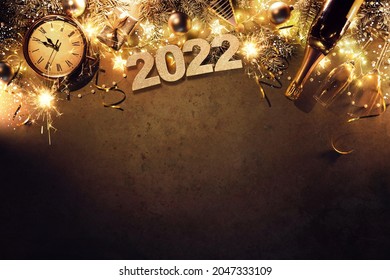 New Years Eve holiday background with fir branches, clock, christmas balls, champagne bottle, gift box and lights on dark board