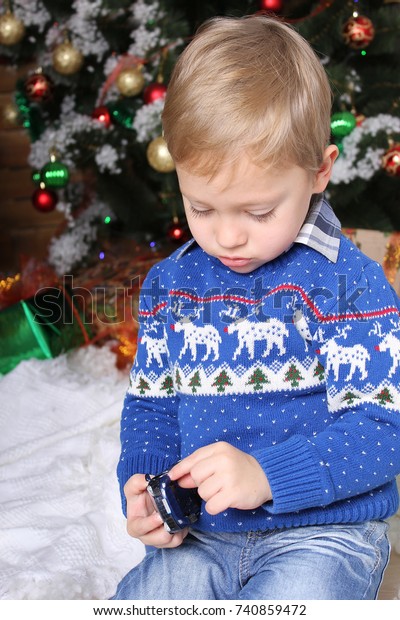 New Year's holidays. A little boy plays a toy car
under the New Year tree.
