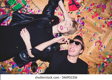 New Year's Party. Girl And Boy Laying On The Floor Full Of Confetti
