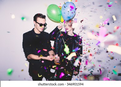 New Year's Party. Girl and boy posing in front of white wall with balloons
