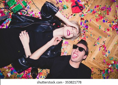 New Year's Party. Girl And Boy Laying On The Floor Full Of Confetti
