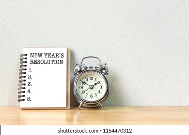 New Years Resolution Concept. Short List To Do Next Year On Book And Clock Vintage On Wooden Table With White Wall