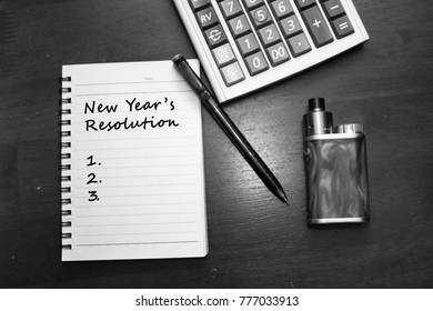 New Year's Resolution Noted With Pen, Calculator And Vape Device On A Wooden Table Black And White