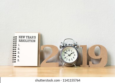 New year's resolution on a notebook and wood number 2019 with clock on wood table and copy space