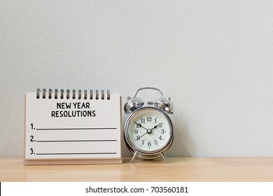 New Year's Resolution On A Notebook And Alarm Clock On Wood Table, Copy Space