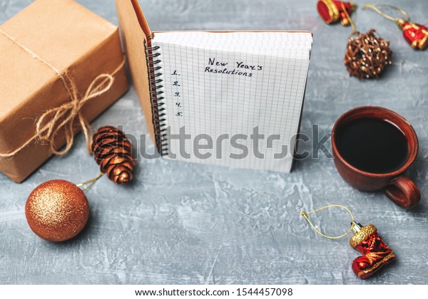 New Year\'s\
resolution, text on the paper in notepad, promises concept, gift\
box, pencil, coffee cup,\
decorations.