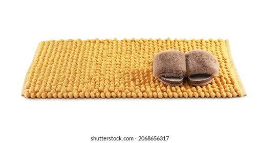 New yellow bath mat and fluffy slippers isolated white