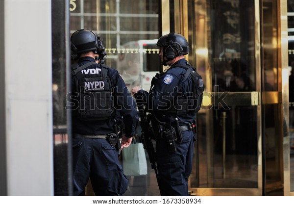 New York, 2020 / March, 2020 / There heavily armed\
police officers, outside Trump Towers NYC talking amongst\
themselves. NYPD logo very clear, very large rifles prominent, with\
their utility belts.