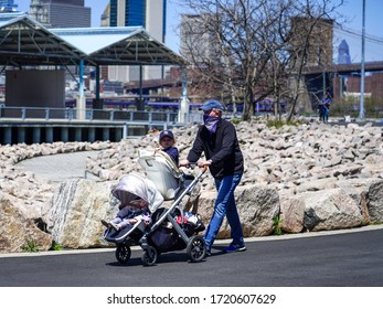 NEW YORK - APRIL 28, 2020: Family Wearing  Face Masks With Kids Enjoy Outdoors During Coronavirus Pandemic At Brooklyn Bridge Park In New York