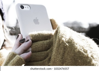 New York, Brooklyn Bridge, USA, January 2018 - Woman taking a selfie holding an iPhone, wearing fingerless mustard colour gloves, with dark nail varnish.