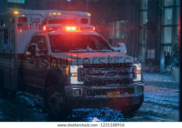 New York, Brooklyn\
/ United States - November 15th 2018: an ambulance flashes its\
lights during a snowstorm