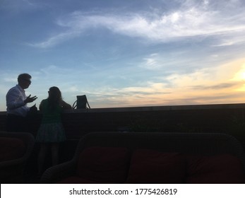 New York City - 17 June 2018: Man And Woman Talking Having Drinks At The Jane Hotel Rooftop Bar In Lower Manhattan In The Evening As The Sun Sets.