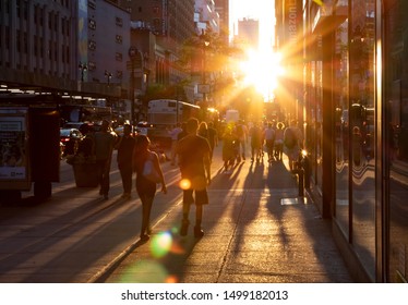 NEW YORK CITY 2019: Crowds Of People Cast Long Shadows As They Walk Into The Bright Light Of Sunset On 34th Street In Midtown Manhattan NYC.