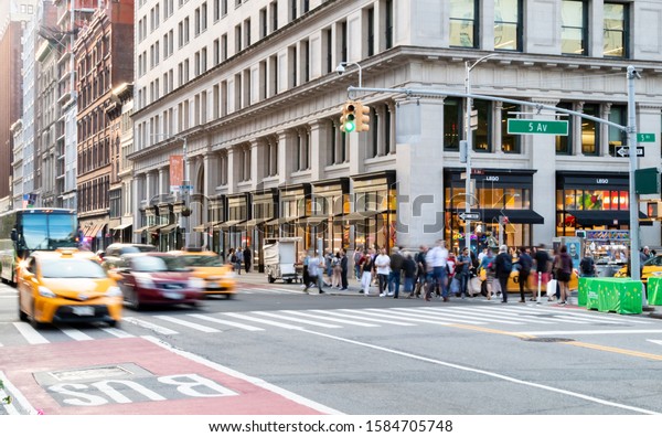 NEW YORK CITY 2019:\
Taxis and people rush through the intersection of 23rd Street and\
5th Avenue during a busy afternoon rush hour commute in Midtown\
Manhattan NYC.