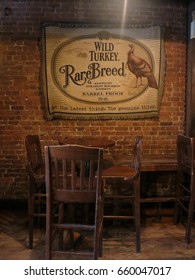 New York City - 26 August 2015:  Wild Turkey Rare Breed Whiskey Throw Blanket Mounted On An Exposed Brick Wall Over Table A Chairs At The Whiskey Ward, A Local Dive Bar On The Lower East Side.