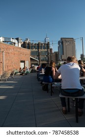 New York City - 26 June 2017: People sitting outside on picnic tables at the rooftop bar of the Arlo Soho Hotel in Manhattan New York. Shallow depth of field.