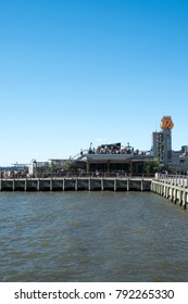 New York City - 3 June 2017: View Of People Drinking At A Hip New York City Rooftop Bar In Lower Manhattan, City Vineyard, On Pier 26 On The Hudson River On A Summer Day, Blue Sky No Clouds.