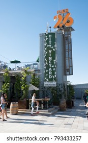 New York City - 3 June 2017: People Walking Passed City Vineyard, A Trendy New York Rooftop Bar In Lower Manhattan At Pier 26 On A Summer Day, Blue Sky With No Clouds. Hip Rooftop Bar In New York City