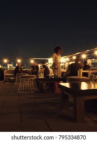 New York City - 30 August 2017: After work happy hour on a chic rooftop in Manhattan. People having a drink of the roof of the The Crown, hip rooftop bar in the Bowery, Lower Manhattan, at night.