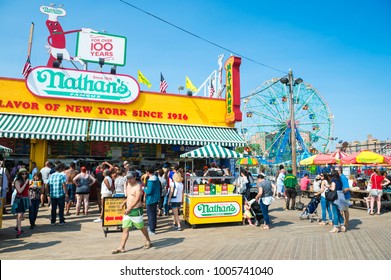 NEW YORK CITY - AUGUST 20, 2017: Visitors Crowd The Iconic Wooden Coney Island Boardwalk Outside The Famous Nathan's Hot Dog Stand On A Hot Summer Day In Brooklyn.