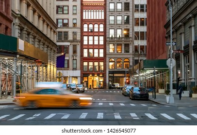 New York City evening street view of the intersection of Washington Place and Broadway in the Greenwich village neighborhood of Manhattan with speeding taxi cab - Powered by Shutterstock