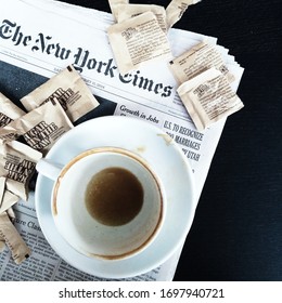 New York City, Fl, USA - February 10, 2014: A Dirty Cup Of Coffee, Empty With Coffee Marks Sitting On Top Of The New York Times Newspaper And Sugar Packets By Sugar In The Raw Are Surrounding It. 