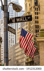 New York City, New York - July 29, 2016: Sign of Wall Street in New York on a street lamp with three American flags and buildings in the background