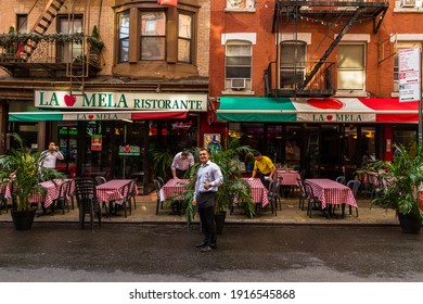 New York City, New York - July 30, 2016: Waiters cleaning tables at the Italian Restaurant "La Mela" in Little Italy and another waiter smiling and posing for the camera with his thumb up 